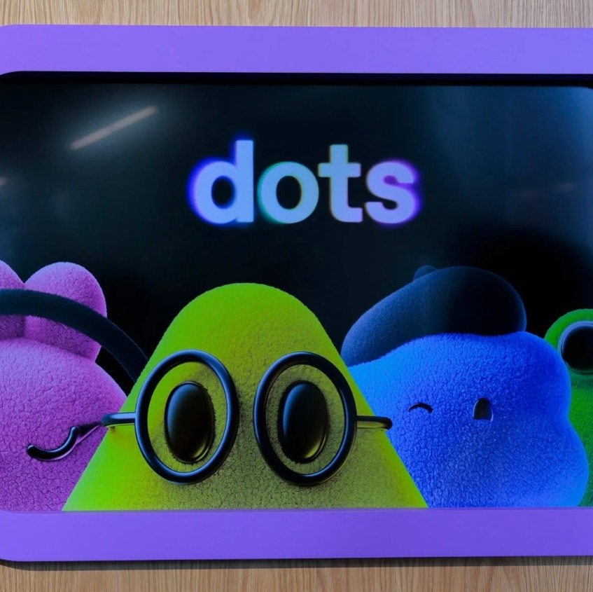 Fuzzy characters on a screen under the word dots at an OpenAI DevDay pop-up