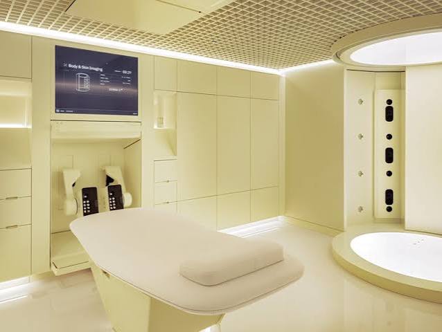 An empty pale Neko Health scan room with an examination bed and imaging equipment built into the walls